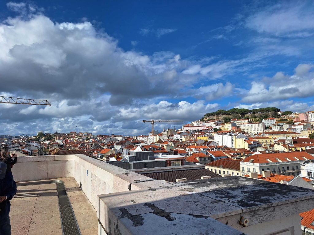 Blick über die Altstadt von Lissabon mit roten Dächern und Castelo de São Jorge – Aussicht bei Sonnenschein auf panikontour.de