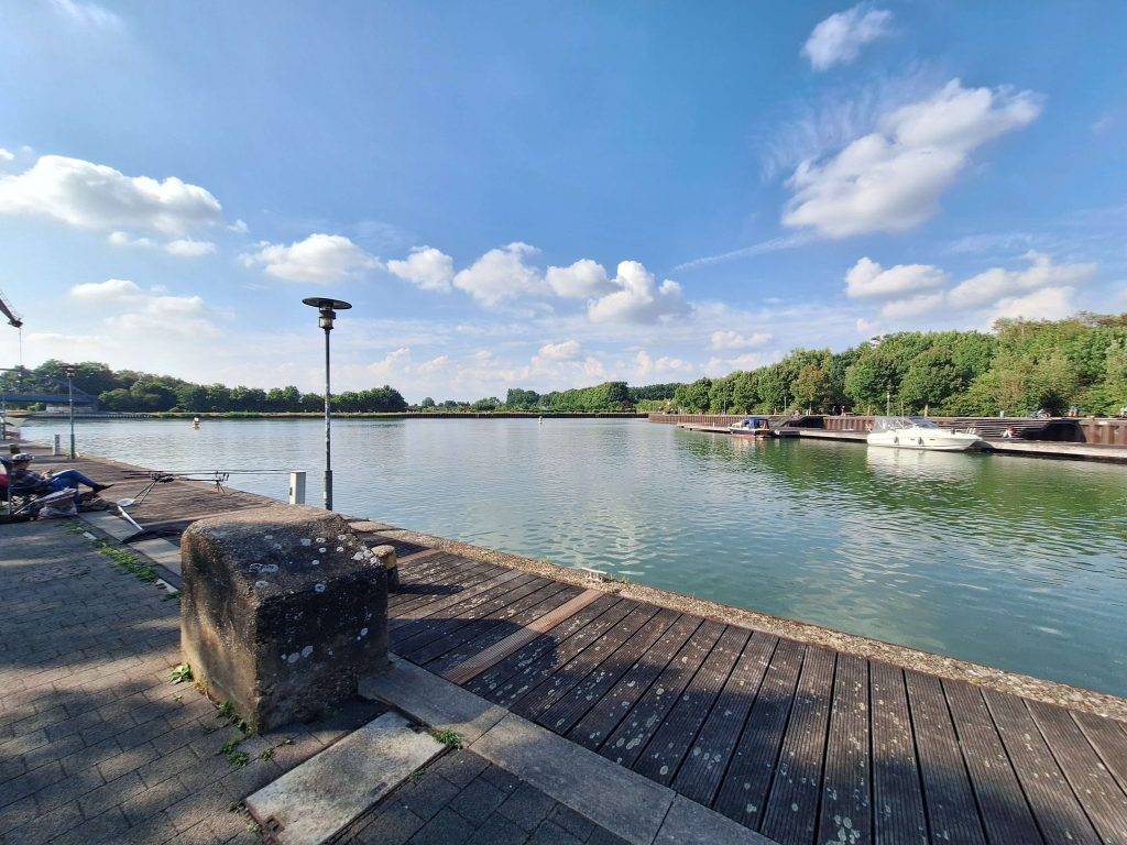 Ruhiger Hafen mit Booten am Kai – Sommernachmittag mit Sonne und Wolken auf panikontour.de