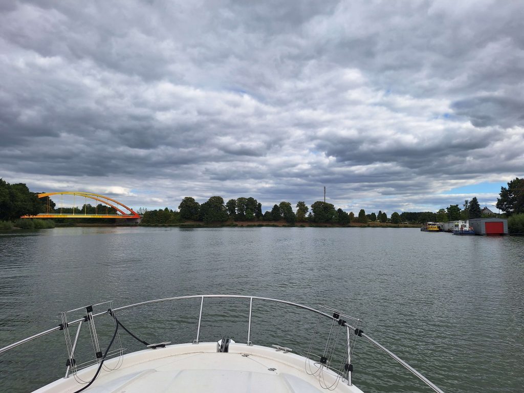 Bootsfahrt auf dem Kanal mit bunter Brücke und bewölktem Himmel – Wasserlandschaft auf panikontour.de