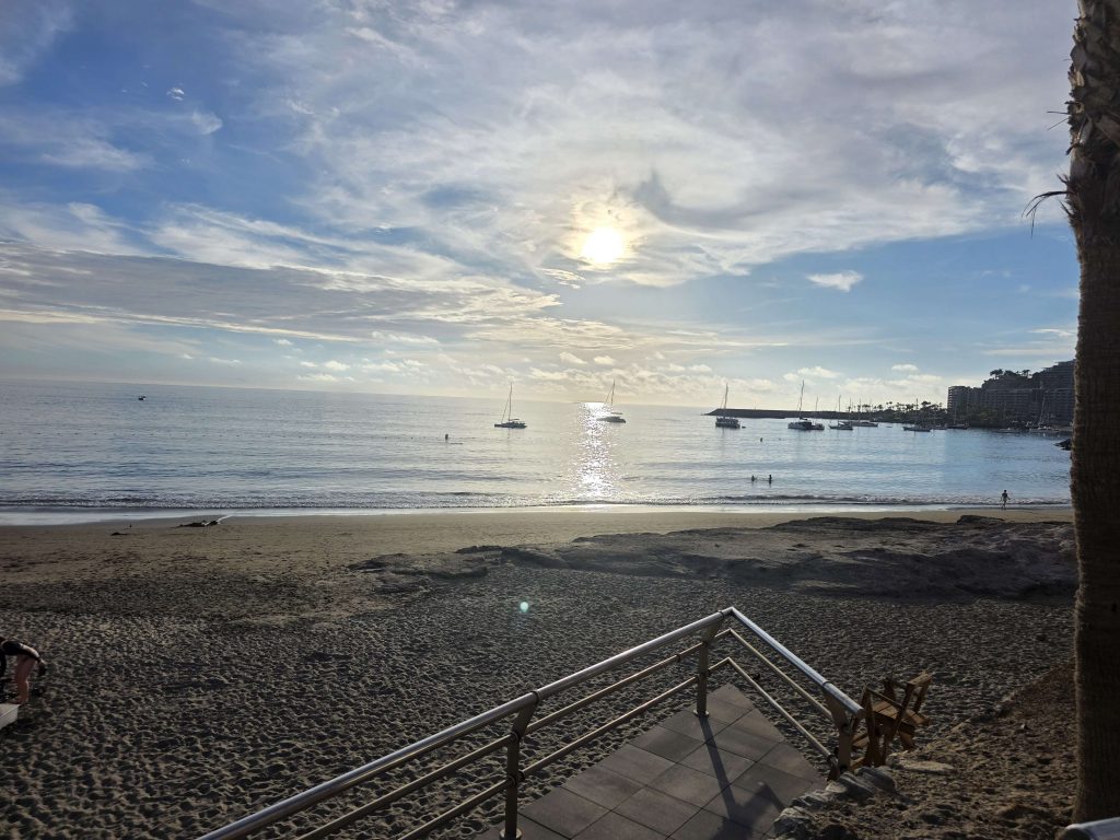 Blick auf den Anfi Beach Gran Canaria am späten Nachmittag mit Sonne, Meer und Segelbooten – Urlaubsfoto auf panikontour.de