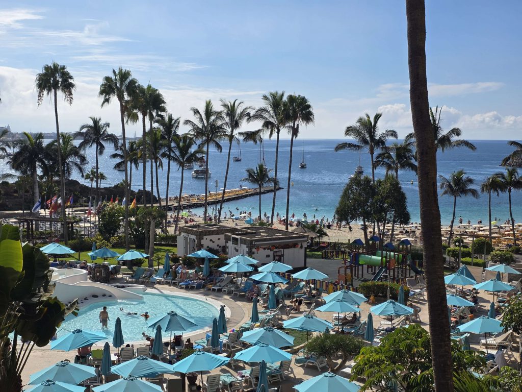 Blick auf den Anfi Beach auf Gran Canaria mit Pool, Palmen und Meer im Hintergrund – sonniges Urlaubsbild auf panikontour.de