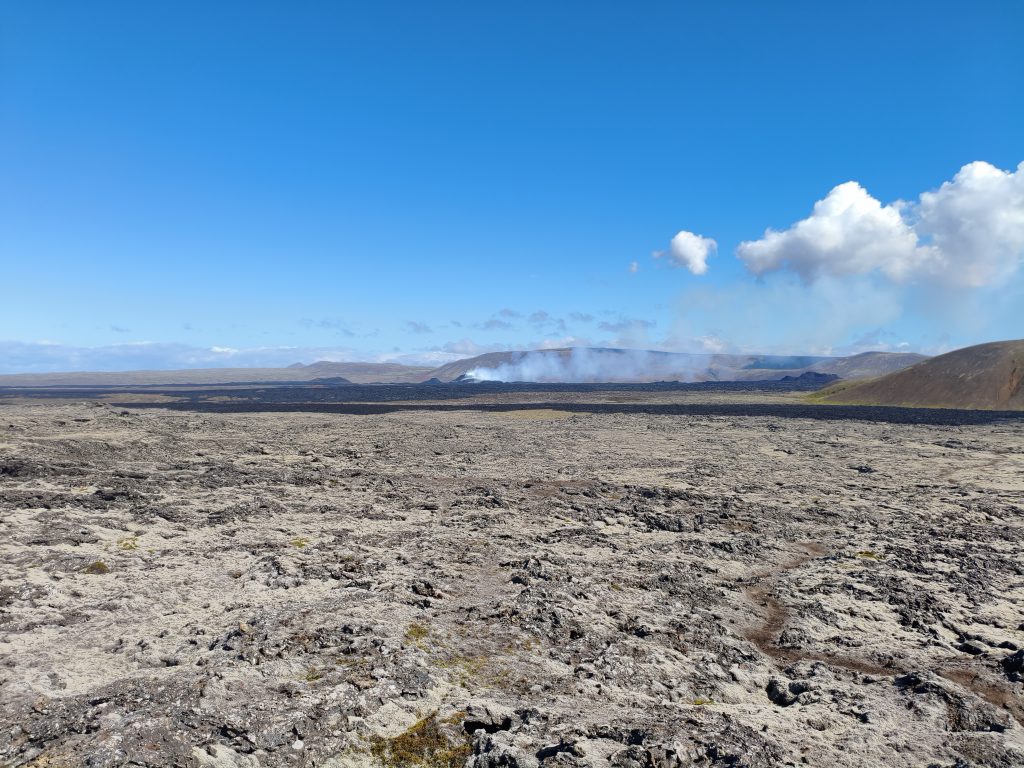 Lavafeld und Rauch bei Rauðhólar auf Island unter blauem Himmel – Naturkraft und Vulkanlandschaft auf panikontour.de