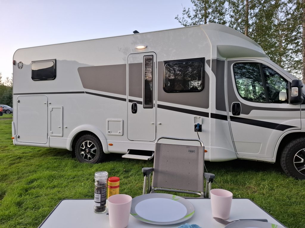 Wohnmobil auf grünem Campingplatz in Island bei Sonnenuntergang – Reise mit Camper auf panikontour.de