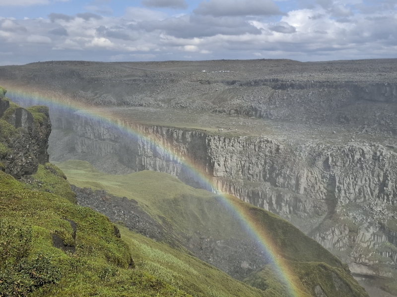 Farbenprächtiger Regenbogen über einer tiefen grünen Schlucht in Island