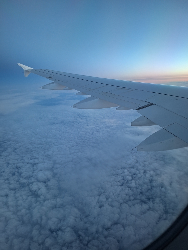 Blick aus dem Flugzeugfenster auf die Wolken – Sonnenaufgang über dem Nordatlantik