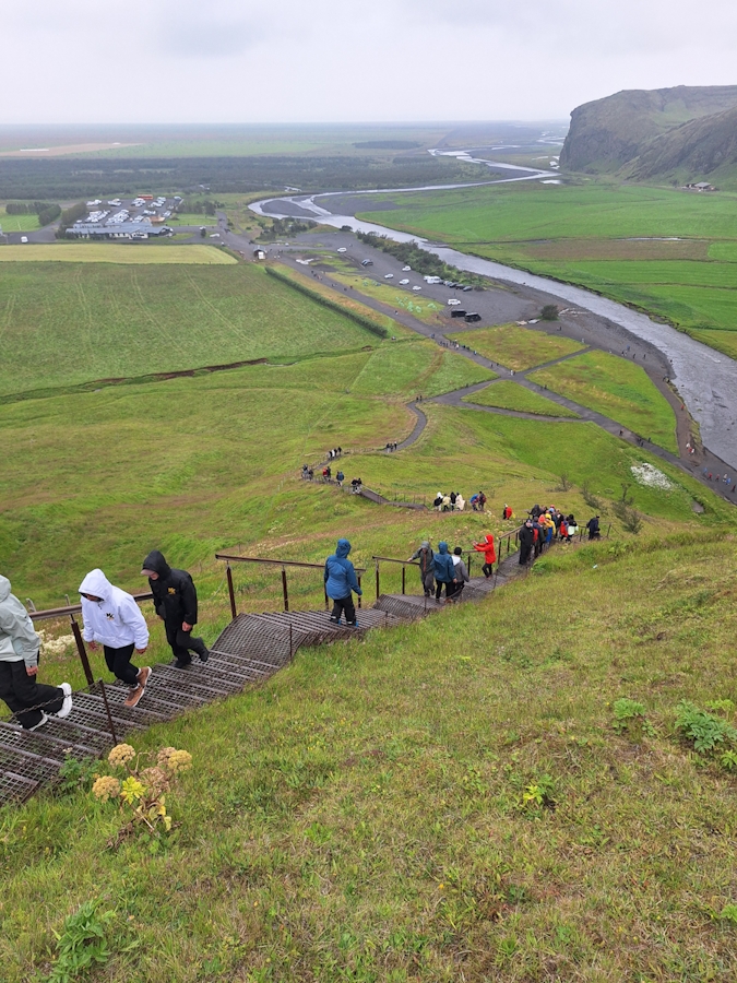 Treppenaufstieg mit Besuchern zum Aussichtspunkt oberhalb des Skógafoss in Island