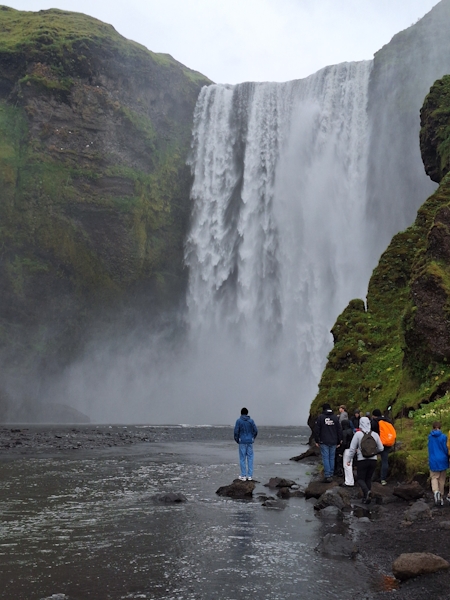 Skógafoss Wasserfall in Island – Besucher am Fuß des mächtigen Wassersturzes