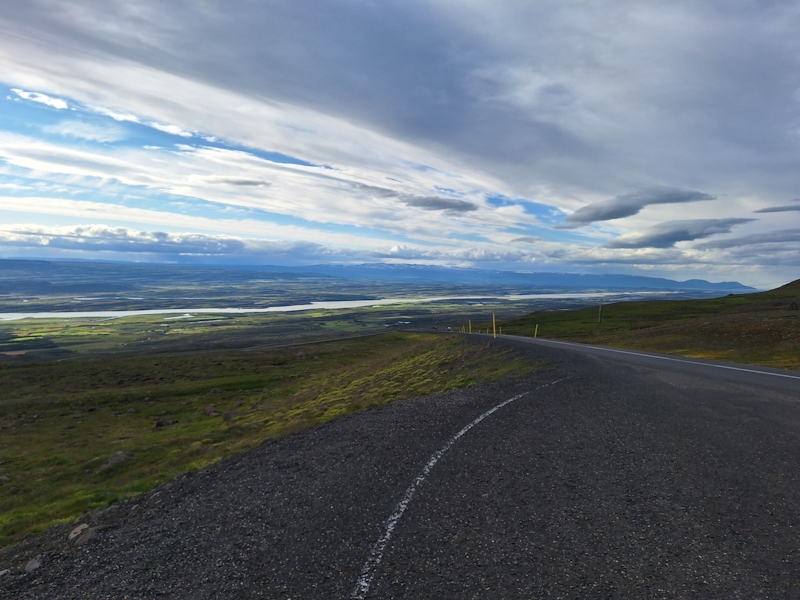 Blick über eine kurvige Bergstraße mit weitem Panorama über das Tal in Ostisland