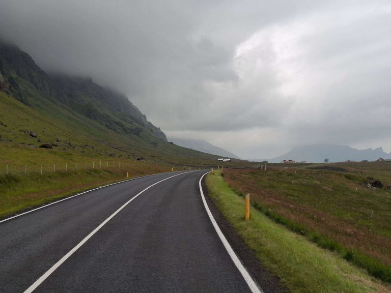 Straße durch die isländische Landschaft unter tiefen Wolken – Symbol für Mut und Gelassenheit auf panikontour.de
